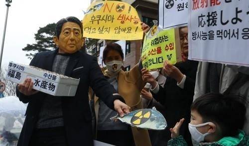 지난 3월 19일 서울 종로구 옛 일본대사관 터 앞에서 열린 ‘일본산 식품 수입규제 WTO 패소 대응 촉구 기자회견’에서 아베 신조의 가면을 쓴 한 참가자가 후쿠시마 방사능 오염 수산물을 강요하는 일본 정부를 규탄하고 WTO 패소에 대한 정부 대응을 촉구하는 퍼포먼스를 벌이고 있다. [연합]