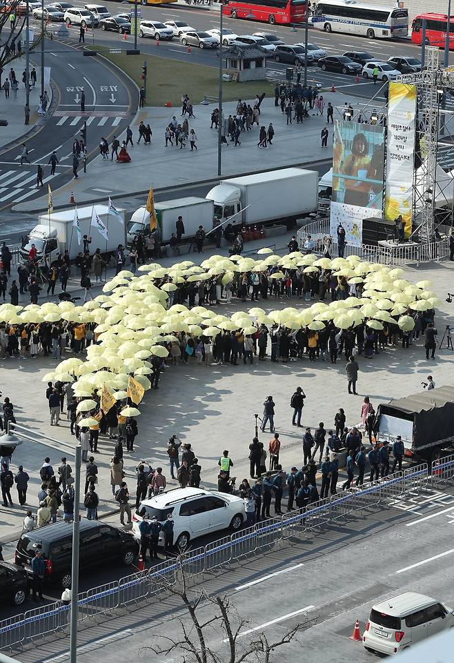 세월호 참사 5주기를 사흘 앞둔 13일 오후 서울 광화문광장에서 참가자들이 노란우산으로 리본을 형상화하는 플래시몹을 하고 있다. [연합뉴스]