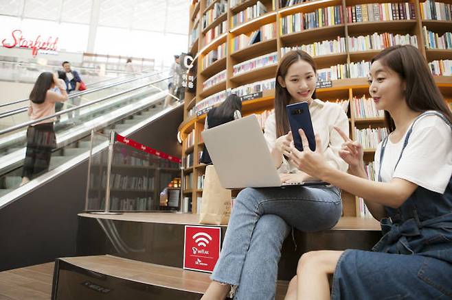 SK텔레콤 홍보 모델이 서울 코엑스에서 T 와이파이 AX 서비스를 이용하고 있다 [사진=SK텔레콤]