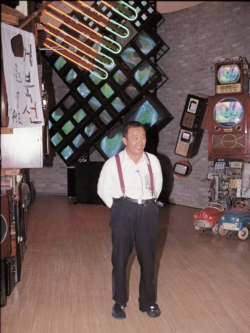 백남준이 1992년 7월 국립현대미술관에서 개막한 ‘백남준 비디오때·비디오땅’ 전시장에서 작품을 둘러보고 있다. 백남준은 낡고 헐렁한 바지에 멜빵을 매고, 자신의 발에 맞춰 천으로 제작한 신발을 신고, 셔츠 앞주머니에는 소지품을 잔뜩 꽂아두는 등 자신만의 독특한 패션으로도 유명했다. /사진제공=국립현대미술관 미술연구센터 소장 김복기 컬렉션