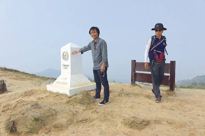 태국 가이드가 푸치파 정상 비석 뒷면에 라오스 국경이라고 쓴 글자를 가리키고 있다. 앞면에는 태국이라고 쓰여 있다.