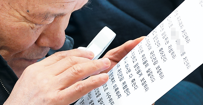 지난달 19일 서울 방송회관에서 열린 대한안마사협회 주최 ‘불법 마사지 인터넷 광고 차단 촉구 결의대회’에 참가한 시각 장애인이 돋보기를 들고 호소문을 읽고 있다. / 연합뉴스