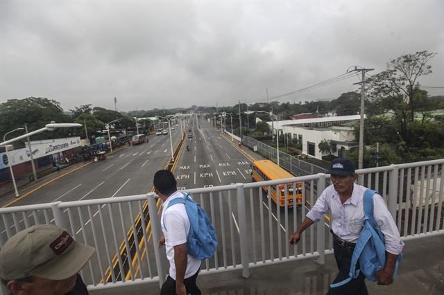 나카라과에서 야권이 정치범 석방을 촉구하는 24시간 총파업이 실시되고 있는 가운데 23일(현지시간) 마나과에서 시민들이 한산한 도로 위의 육교를 지나가고 있다.  AP 연합뉴스
