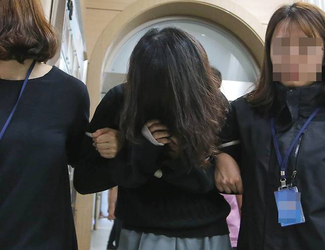 신상공개가 결정된 '전 남편 살해' 피의자 고유정(36)이 6일 오후 제주 동부경찰서에서 조사를 받은 뒤 머리카락으로 얼굴을 가린채 유치장으로 향하고 있다. [뉴시스]