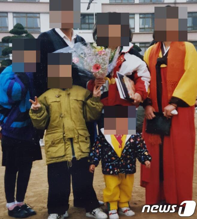 예비신부 큰언니의 중학교 졸업식 당시 온 가족이 함께 찍은 사진. 예비신부가 노란색 저고리 옷을 입고 맨 앞 중앙에 서 있다.(유가족 제공) /© 뉴스1