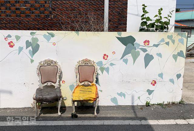 작품일까, 쉼터일까. 꽃 그림 담장에 낡은 의자 두 개가 나란히 놓여 있다.