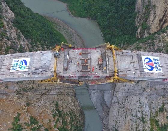 중국 남서부 쓰촨(四川)성, 구이저우(九州), 윈난(雲南)성 접경지역에 위치한 아치교가 협곡 위에 7일(현지시간) 연결됐다. 아치교 위에 올려질 주 대교는 올 연말 완공될 예정이다. [신화=연합뉴스]