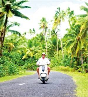 스쿠터를 타고 라로통가섬 여행을 즐기는 여행객