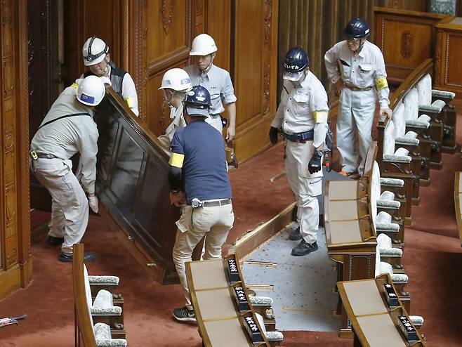 일본 참의원 관계자들이 지난달 28일 본회의장에서 중증장애인 후나고 야스히코 의원과 기무라 에이코 의원의 자리를 만들기 위해 작업하고 있다. [로이터=연합뉴스]