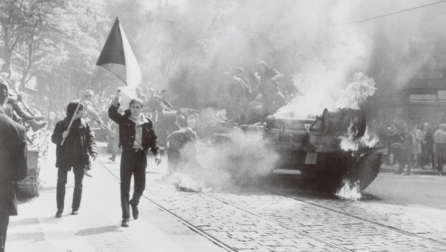 프라하의 봄이 시작된 1968년 소련이 체코슬로바키아를 침공하는 동안, 프라하에서 체코슬로바키아인이 불타는 탱크 옆으로 국기를 흔들고 있다. [The Central Intelligence Agency]