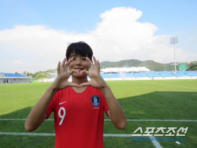 여자축구 U-15 대표팀 주장 전유경이 손가락 하트를 그려보이며 환하게 웃고 있다.