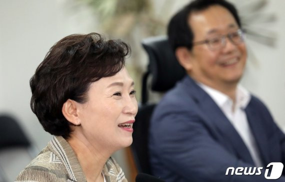 김현미 국토교통부 장관이 12일 서울 여의도 국회에서 열린 민간택지 아파트 분양가 상한제 시행을 위한 비공개 당정협의회에서 의원들과 인사말을 나누며 활짝 웃고 있다.
