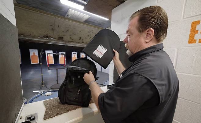 방탄 가방 업체인 터피팩의 CEO 스티브 나레모어가 9일(현지시간) 휴스턴의 한 사격 연습장에서 방탄 효과를 테스트 하기 위해 터피팩에 탈착식 탄도 보호막을 넣고 있다. [AP=연합뉴스]