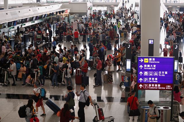 홍콩 국제공항에서 13일 오전 항공기 운항이 재개돼 승객들이 탑승수속창구 앞에 줄을 서 있다. 홍콩=로이터 연합뉴스