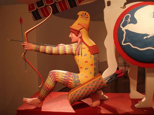 그리스 에기나섬 아파이아 신전(기원전 약 500년)의 궁수 조각상. 대리석 조각에서 발견된 물감의 흔적을 통해 채색되었던 과거의 형태를 재현한 모습. 출처: Marsyas, 위키커먼즈