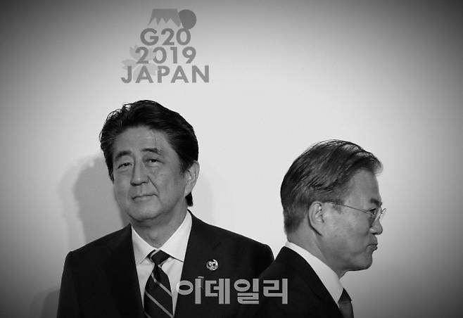 △6월 29일 일본 오사카에서 열린 주요20개국·지역(G20) 정상회담을 참여한 문재인 대통령이 아베 신조 일본 총리와 악수한 뒤 지나가고 있다.[사진=AFP제공]