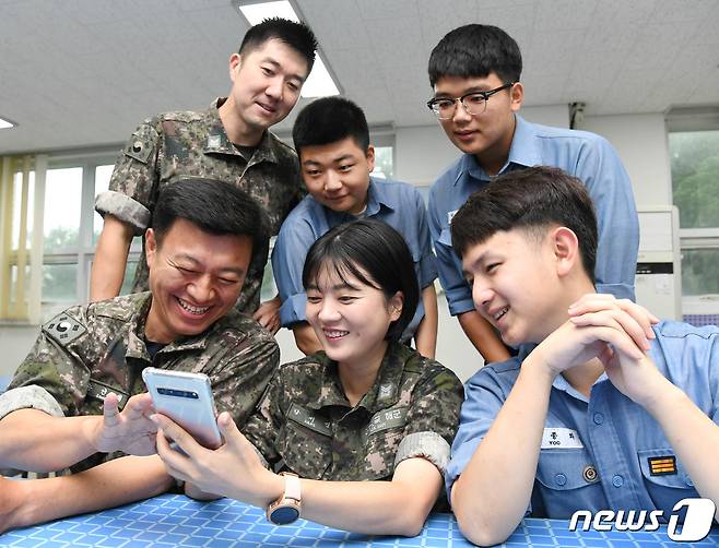 해군이 여군의 날을 앞둔 5일 덕적도 기지에 아이를 데리고 자원해 간 전탐부사관 강서연 중사를 소개했다. 강서연 중사(가운데)가 동료들과 아이 사진을 보며 환하게 웃고 있다.(해군 제공) 2019.9.5/뉴스1