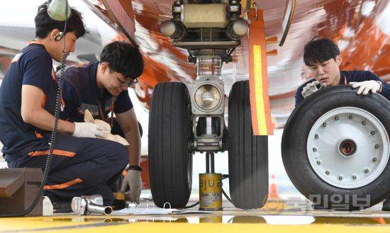 비행기 앞 타이어 마모 상태를 확인한 정비사들이 새로운 타이어로 교체 준비를 하고 있다.