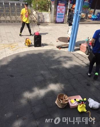홍대 길거리에서 김건모의 ‘잘못된 만남’을 공연하고 있는 청년. 클라이막스로 갈수록 더 많은 웃음을 준다. 그의 개성이 좋아 공연 모금함에 노란색 비타민 한상자를 넣었다./사진=남형도 기자
