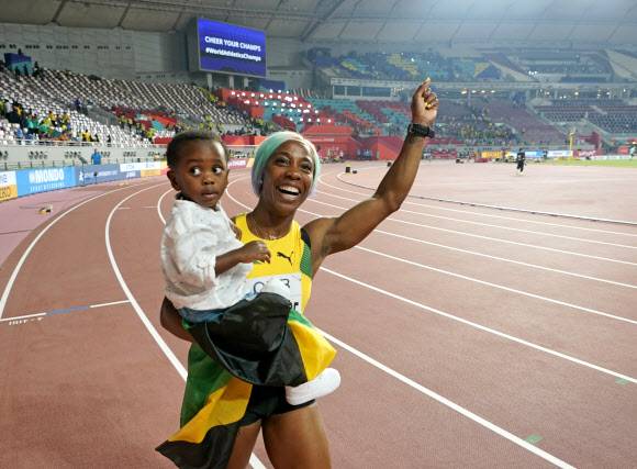 자메이카 육상 선수 셸리 앤 프레이저-프라이스가 29일(현지시간) 카타르 도하에서 열린 세계육상선수권대회 여자 100m 결선에서 금메달을 따낸 뒤 아들 지온과 기뻐하고 있다. 이날 프레이저-프라이스는 10초 71로 올 시즌 최고 기록을 세웠다. AP 연합뉴스