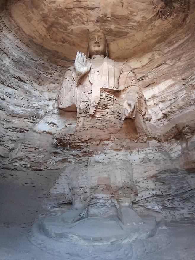 북위 왕조가 만든 중국의 대표적 석굴사원 윈강석굴의 16굴 본존상. 다른 석불과 달리 소매가 넓고 넓은 띠를 두른 중국풍 의상을 둘렀다. 460년 석굴을 처음 뚫은 북위 황제 문성제의 풍모를 담고 있다는 게 통설로 알려져 있다.