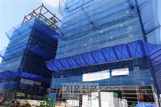 우수 - 인천 영종도에서 의성건설이 공사하고 있는 건축물 외관. 일반 강관 비계보다 안전한 시스템 비계가 건물 외벽을 촘촘히 둘러싸고 있다. 외벽에 날개처럼 보이는 것은 낙하물 방지망이다.