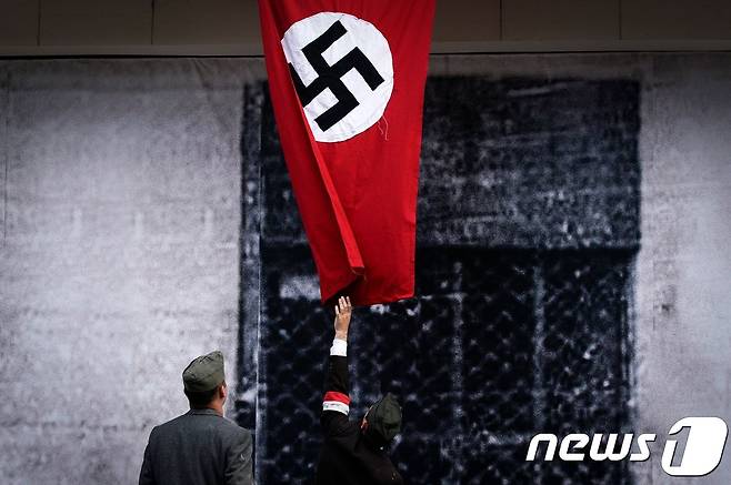폴란트 레지스탕스 복장을 한 공연가가 8월3일(현지시간) 폴란드 수도 바르샤바에서 제2차 세계대전 75주년을 기념해 공연하고 있다. 사진 속 깃발은 독일 나치즘의 상징 하켄크로이츠. © AFP=뉴스1