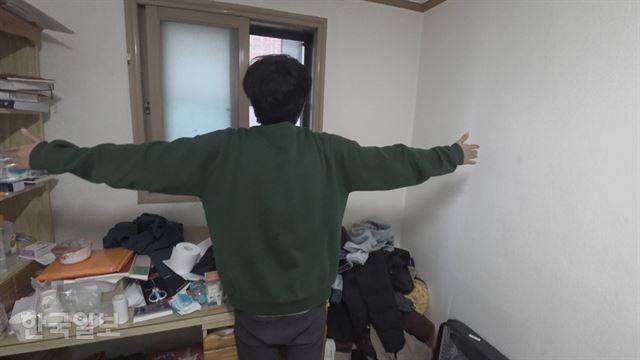 대학생인 고근형씨가 서울 관악구 고시원의 자기 방 안에서 양 팔을 벌려 폭을 재 보고 있다. 옷장이 없는 그의 방에는 항상 옷이 한 켠에 쌓여있다. 박상준 기자 [저작권 한국일보]