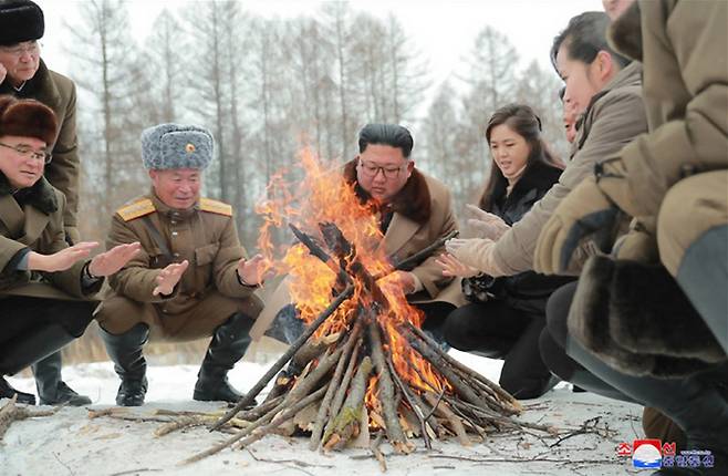 김정은 북한 국무위원장이 리설주 여사와 군 간부들과 함께 군마를 타고 백두산에 올랐다고 조선중앙통신이 4일 보도한 사진이다. 김 위원장이 간부들과 모닥불을 쬐고 있다. [사진=연합뉴스]