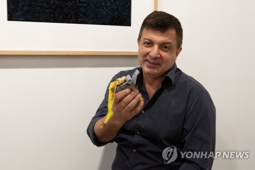 뉴욕에서 활동하는 행위예술가 데이비드 다투나는 7일(현지시간) "배가 고프다"며 관중 앞에서 '코미디언'에 사용된 바나나를 먹었다. [로이터=연합뉴스]