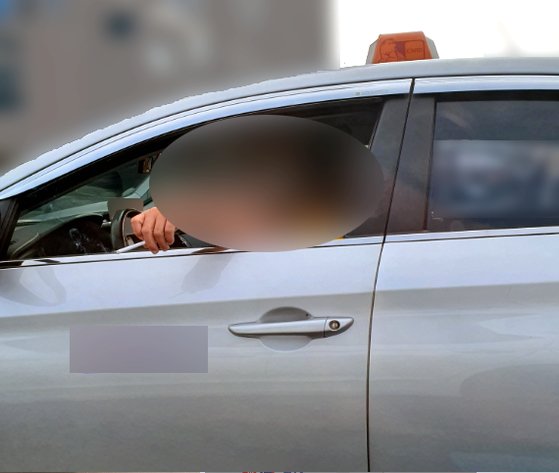 한 택시기사가 택시 안에서 담배를 피우다 담뱃재를 창밖으로 털고 있다. 현행법상 기사가 택시 안에서 흡연하면 행정처분 대상이다. [사진 서울시]