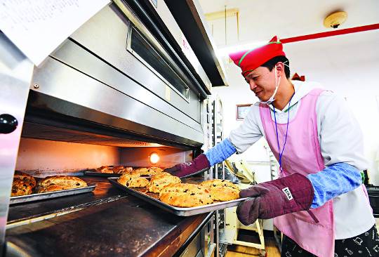 제과제빵부 지적장애인 김지한씨가 오븐에서 직접 만든 빵을 꺼내고 있다. 빵은 군부대에 납품하고 지역사회에 판매된다.