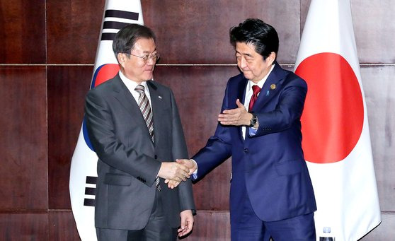 문재인 대통령(왼쪽)과 아베 신조 일본 총리가 24일 중국 쓰촨성 청두 세기성 샹그릴라호텔에서 열린 정상회담에서 악수하고 있다. 이날 중국 공산당 기관지 인민일보는 1면 상단에 한·중 정상회담을, 하단에 중·일 정상회담 소식을 각각 게재했다. [청와대사진기자단]