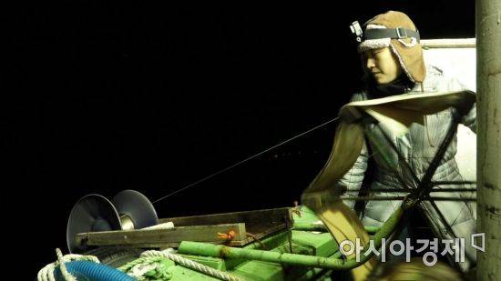 울릉군 저동항에서 출발한 11톤급 채낚기 어선이 8시간 조업한 결과, 치어와 한치를 포함해 오징어 22마리를 잡는 것이 전부였다. 저동항에 정박된 어선들의 한 달 조업일수는 열흘 안팍으로 나타났다. 수동 조상기를 통해 오징어 낚시에 나선 기자의 모습. 사진 = 이경도 PD