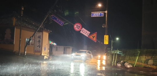 지난 7일 오후 9시 부산 기장군 대변리 동해어업관리단 입구의 도로표지판 지주대가 강풍에 부러져 전봇대에 걸려 있다./부산경찰청 제공