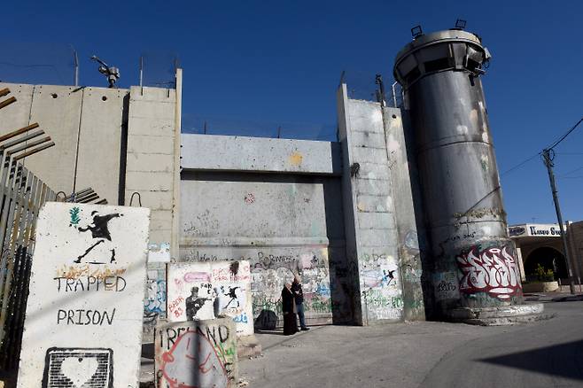 예수 탄생지인 베들레헴을 에워싼 이스라엘의 분리장벽과 감시탑 앞에 23일 팔레스타인 주민들이 서 있다. &nbsp;베들레헴 | UPI연합뉴스