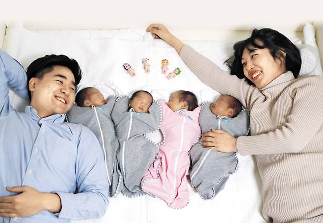 경기도 부천시에 사는 이한솔(31)·나혜승(31)씨 부부가 작년 12월 22일 네쌍둥이를 낳았다. 자연 임신으로 낳은 사란성(四卵性) 쌍둥이 태명은 봄·여름·가을·겨울. 아빠가 총각 시절 아이 넷을 낳겠다며 지은 태명인데 현실이 됐다. 그래서 이씨 별명은 ‘춘하추동 아빠’다. 지난 19일 여섯 식구가 사는 아파트 안방에서 아빠(사진 맨 왼쪽)와 엄마가 네쌍둥이를 바라보며 환하게 웃고 있다. 아빠 옆에 태어난 순서대로 누워 있는 봄(하온)·여름(하민)·가을(하음)·겨울(하준) 머리맡에는 아빠 친구가 선물한 인형 네 개가 놓여 있다. /장련성 기자