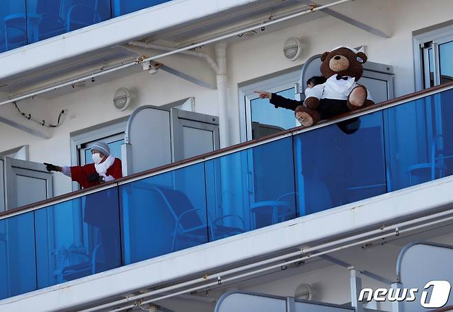 일본 요코하마항에 정박 중인 대형 크루즈선 '다아이몬드 프린세스' 승객들이 11일 선실 발코니에 나와 바깥 풍경을 가리키며 대화를 나우고 있다. © 로이터=뉴스1