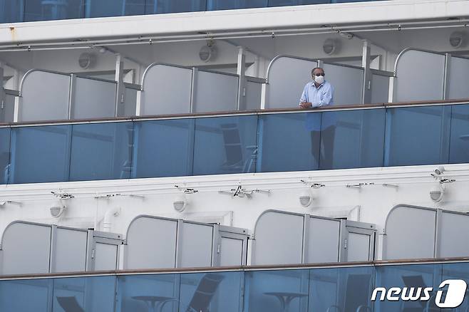 14일 요코하마항에 강제 격리된 채 정박해 있는 다이아몬드 프린세스호에서 마스크를 쓴 승객이 발코니에 나와 있다. © AFP=뉴스1 © News1 우동명 기자