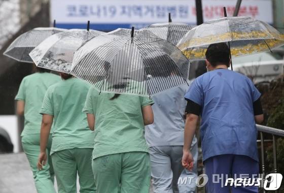 (대구=뉴스1) 공정식 기자 = 신종 코로나바이러스 감염증(코로나19) 확산이 계속되는 25일 오후 코로나19 지역거점병원인 계명대학교 대구동산병원에서 근무를 마치고 나와 보호구를 모두 해제한 의료진이 우산을 쓰고 무거운 발걸음을 옮기고 있다. 2020.2.25/뉴스1  <저작권자 ⓒ 뉴스1코리아, 무단전재 및 재배포 금지>