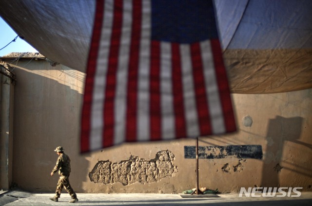 [ 카불(아프가니스탄)= AP/뉴시스] 아프가니스탄에 주둔하고 있는 미군 제 27보병연대의 한 병사가 커다란 성조기가 드리워져 있는 막사 앞을 걸어가고 있다. (AP 자료사진) 미국은 18년간의 아프간 전쟁을 끝내고 미군을 철수시키기 위해 29일 탈레반측과 평화협상을 체결할 예정이다. 2020.2.29.