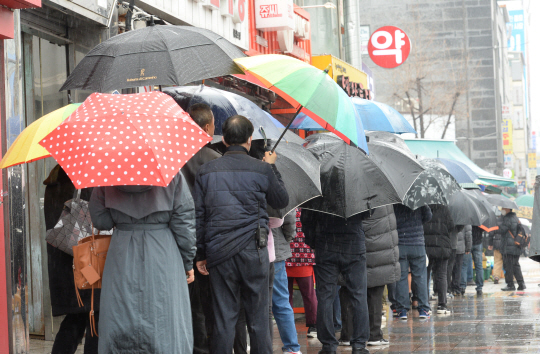 마스크 구매행렬 : 마스크 5부제 시행 이틀째인 10일 오전 전국에 봄비가 내리는 가운데, 서울 종로6가 한 약국에서 우산을 쓴 시민들이 마스크를 구매하기 위해 줄을 서고 있다.   김호웅 기자
