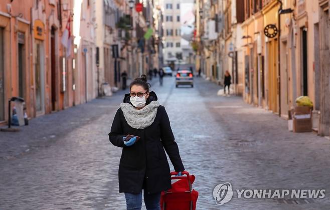 '전국 이동제한령' 이탈리아 로마의 한산한 거리 (로마 로이터=연합뉴스) 신종 코로나바이러스 감염증(코로나19)이 무서운 속도로 확산하는 이탈리아에서 전례 없는 전국 이동제한령이 발효된 지 사흘째를 맞은 12일(현지시간) 로마에서 한 여성이 마스크를 쓴 채 거의 인적이 끊긴 거리를 지나가고 있다. leekm@yna.co.kr