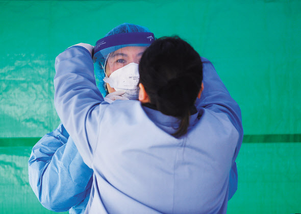 26일(현지시간) 미국 워싱턴 주 시애틀에서 의료진들이 서로에게 보호장비를 착용해주고 있다. [로이터]