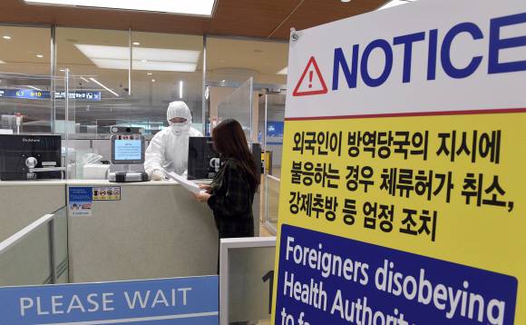 코로나19가 급속도로 퍼지기고 있는 유럽,미주 거주 교민들이 전세기편으로 대거 입국하고 있는 8일 전신 방호복을 입은 인천공항국제공항 출입국 외국인청 입국심사관이 유증상자 전용 입국심사대에서 입국심사뒤 자가격리 지침을 설명하고 있다. 2020.4.8    이종원 선임기자 jongwon@seoul.co.kr