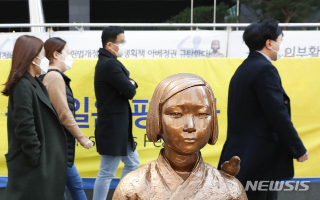 [서울=뉴시스] 박민석 기자 = 일본군 성노예제 문제해결을 위한 제1431차 정기수요시위가 온라인으로 생중계된 18일 오후 서울 종로구 옛 일본대사관 앞에서 마스크를 착용한 시민들이 평화의 소녀상 뒤로 지나가고 있다. 2020.03.18.mspark@newsis.com