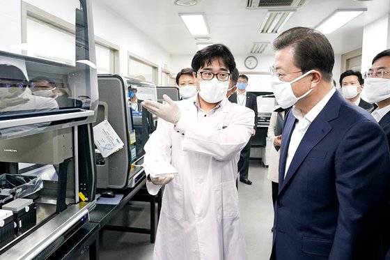 문재인 대통령이 3월 25일 서울 송파구의 신종 코로나 감염증(코로나19) 진단시약 긴급사용 승인 기업 연구실을 방문해 관계자들로부터 설명을 듣고 있다. 문 대통령은 ’방역은 여러분으로부터 시작된다“고 격려했다. [청와대사진기자단]