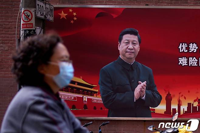 중국 상하이에서 시진핑 국가 주석 사진 앞을 마스크를 쓴 한 시민이 지나가고 있다. © 로이터=뉴스1