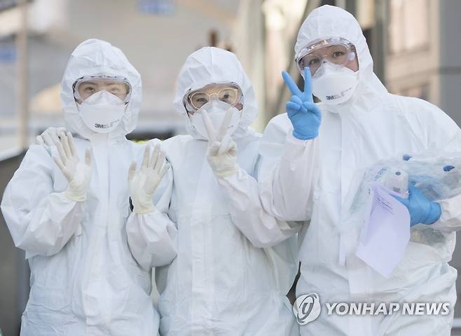 '훗날 즐거웠던 추억으로 남길' 3월 11일 대구시 중구 계명대학교 대구동산병원에서 의료진이 교대 근무를 위해 방호복을 입고 신종 코로나바이러스 감염증(코로나19) 환자들이 있는 병동으로 향하며 취재진을 향해 브이를 그리고 있다. [연합뉴스 자료사진]