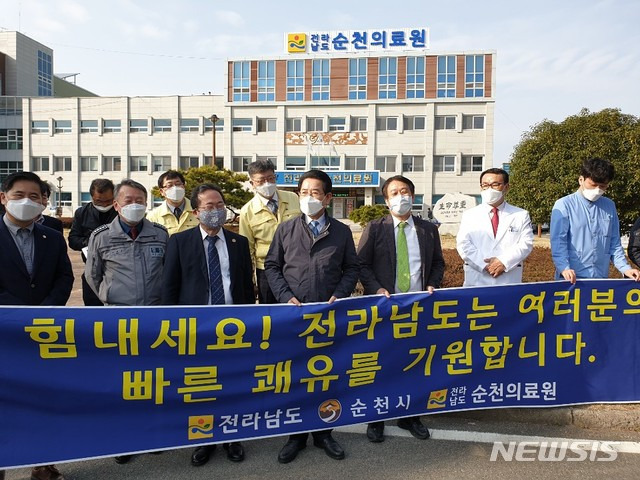 [순천=뉴시스]김석훈 기자 = 대구지역 코로나19 경증환자 30명이 13일 순천의료원에서 치료받기 위해 버스를 타고 도착하자 병원앞에 나온 김영록 전남도지사와 허석 시장, 순천시민이 나와 쾌유를 비는 현수막을 들고 있다. (사진=순천시청 제공) 2020.03.13. photo@newsis.com